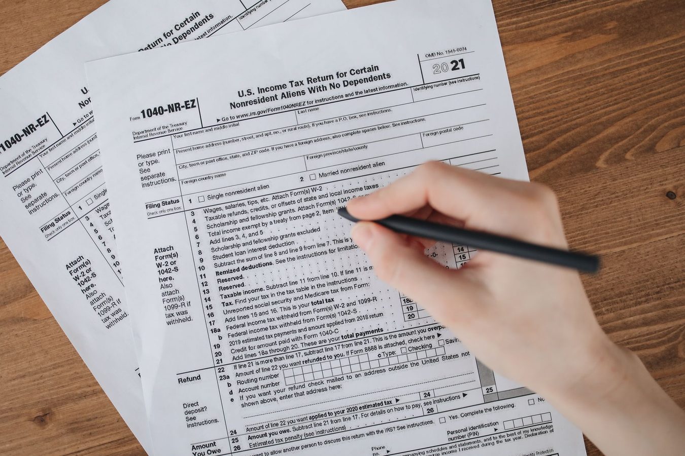 A student sitting at a desk reviewing printed tax forms and a laptop
