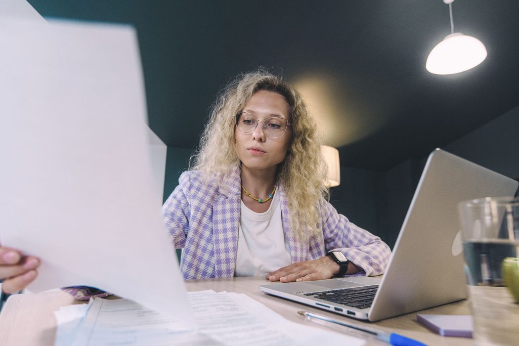 A student reviewing tax documents and a laptop at a desk while researching filing steps